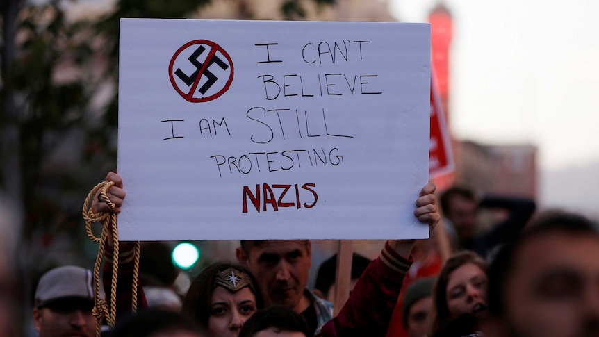A protest sign reads 'I can't believe I am still protesting Nazis'