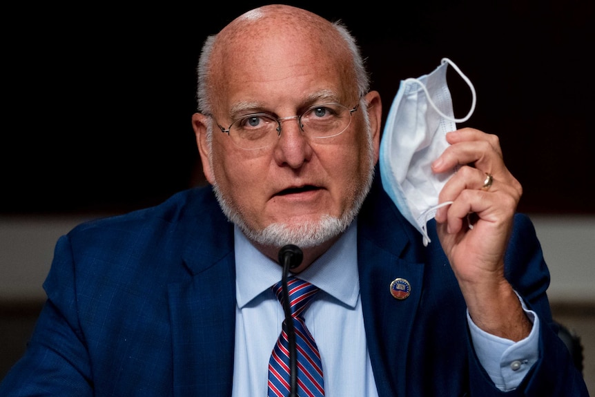 Centers for Disease Control and Prevention Director Dr. Robert Redfield holds up his mask