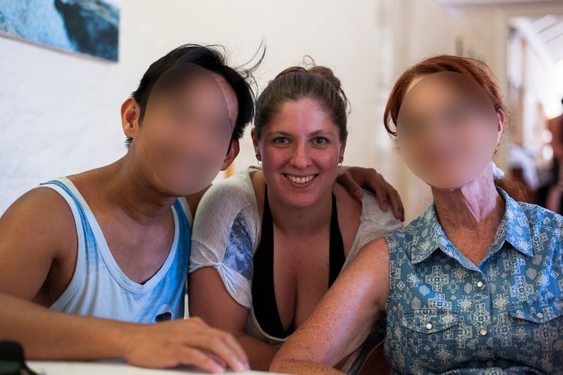 Alison Raspa with friends, one has his arm over her shoulder. Faces except Alison's are blurred.