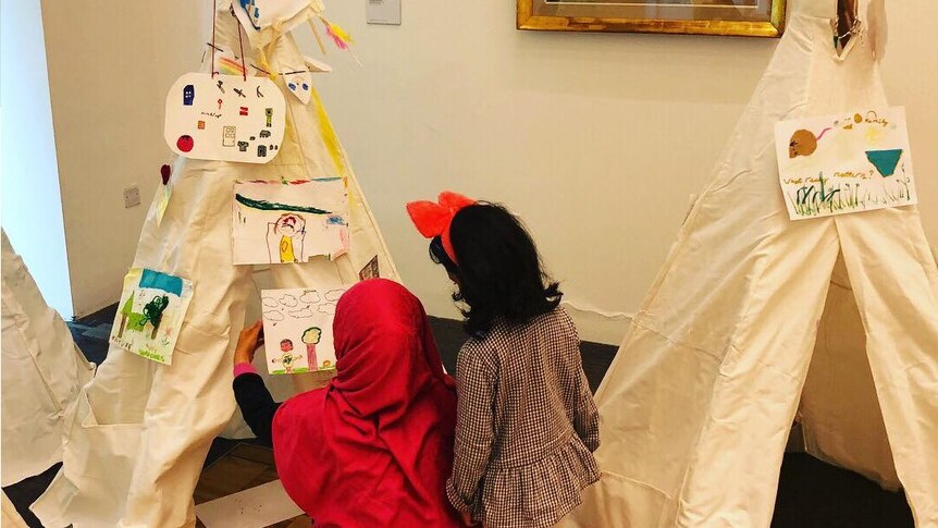 two children creating tepees together with artwork
