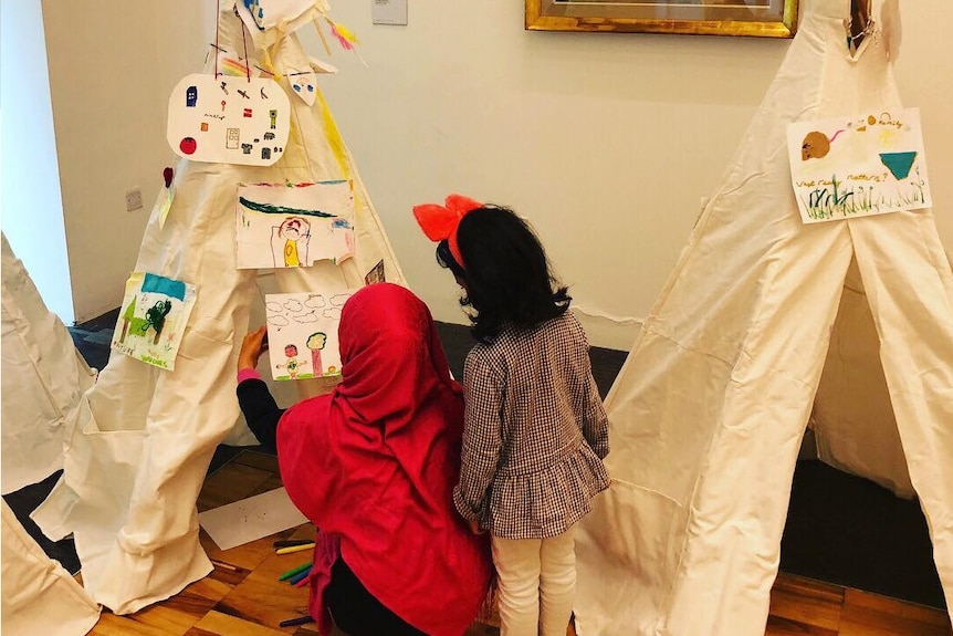 two children creating tepees together with artwork