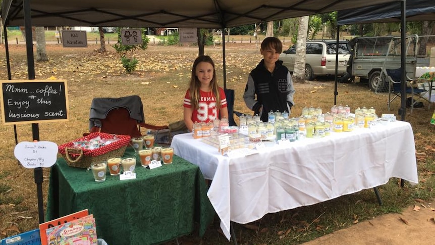 a young boy and girl standing with candles to sell them