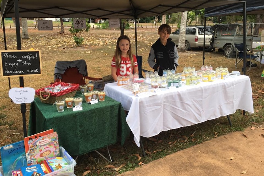 a young boy and girl standing with candles to sell them