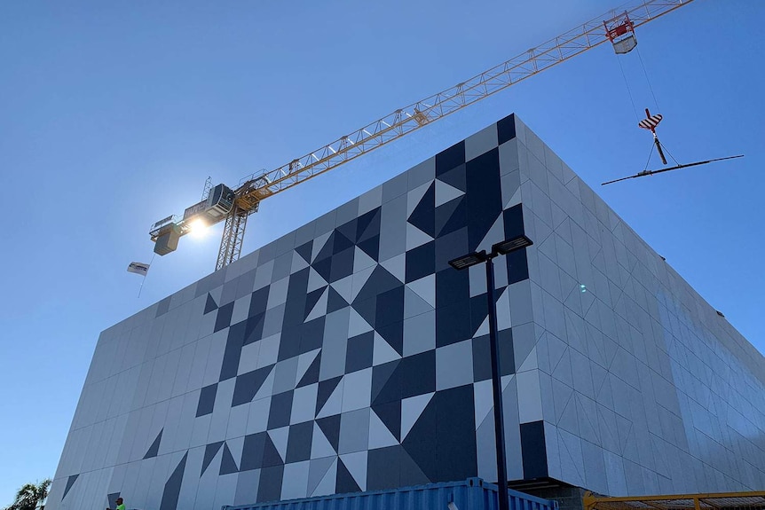 A crane hovers over a large building under construction