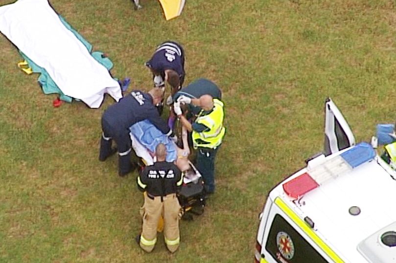 Paramedics working on a teenager on a stretcher.