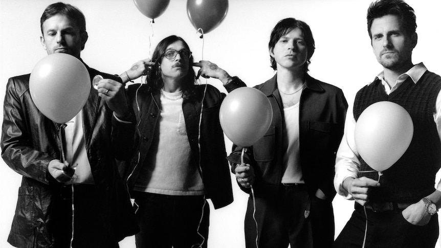 Black and white photo fo Kings of Leon holding balloons.