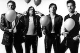 Black and white photo fo Kings of Leon holding balloons.