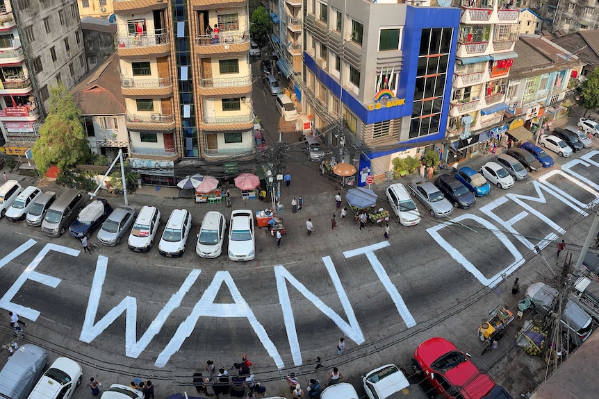 We Want Democracy written on street lined by cars, buildings