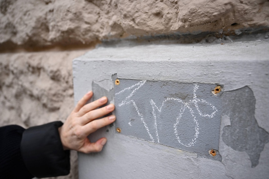 A hand touches the place of a disappeared metal plaque which was a tribute to a victim of Joseph Stalin.