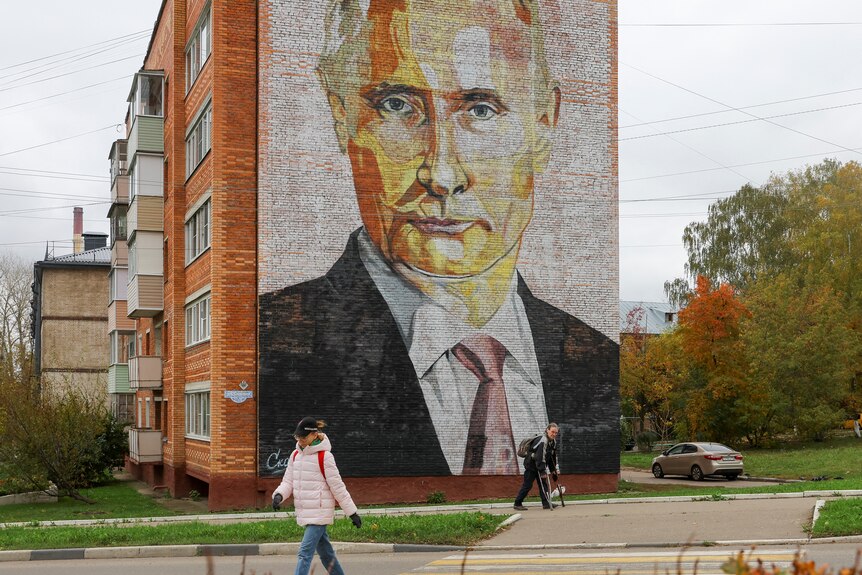 A mural of Vladimir Putin looking stern on the side of an apartment building.