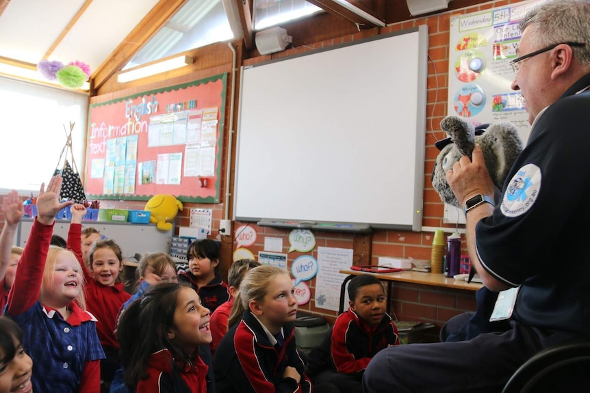 David Packwood holds the Kenny Koala puppet as students raise their hands.