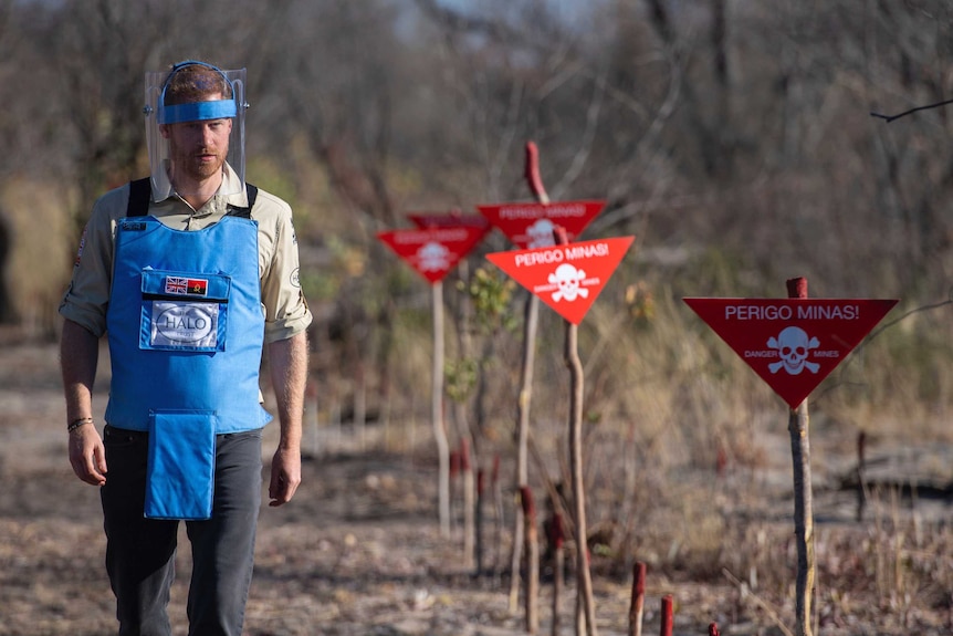 Britain's Prince Harry walks through a minefield in Dirico while wearing a blue protective outfit