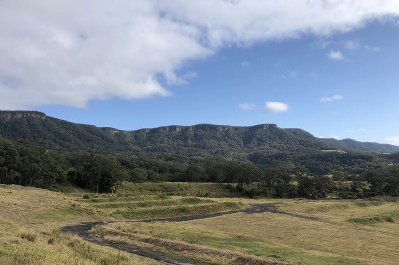 Sweeping view of vacant grassy land with mountains in the background.