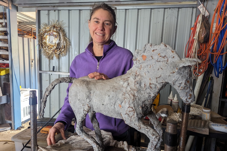 A smiling Heather Barrett with a great sculpture of a horse 