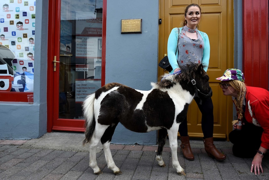 A woman stands on the streets of Killorglin, Ireland, with her pony.