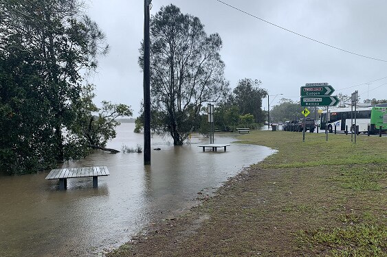 A flooded street with a sign pointing to Ballina