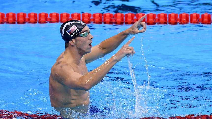 Michael Phelps points his hands in the air after another race win