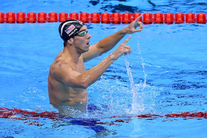 Michael Phelps points his hands in the air after another race win