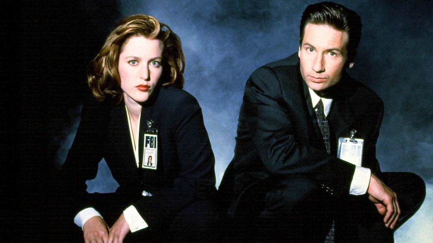 Fictitious FBI agents Dana Scully and Fox Mulder crouch looking at the camera, a promotional shot from the first X Files series