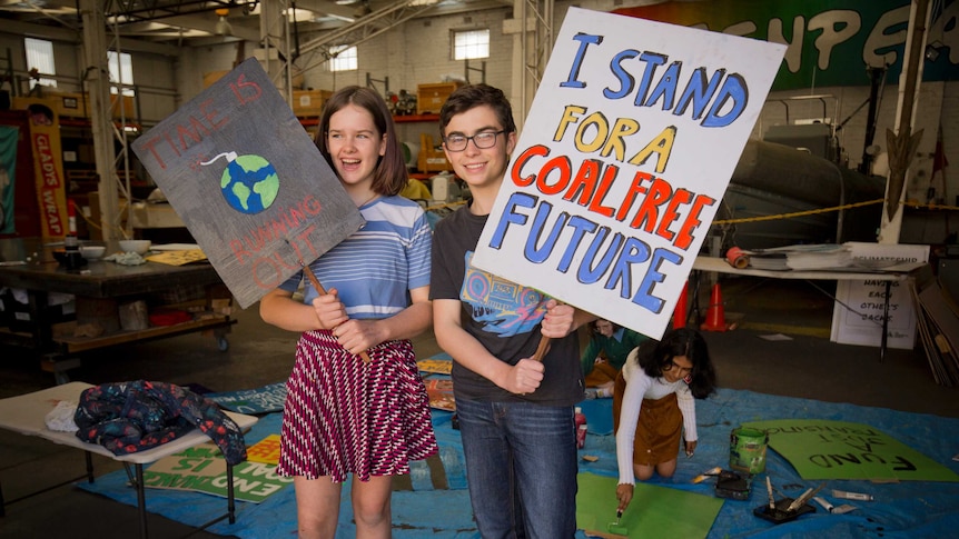 Two young people holding up placards: one reads, 'I stand for a coal free future' and the other says, 'Time is running out'.