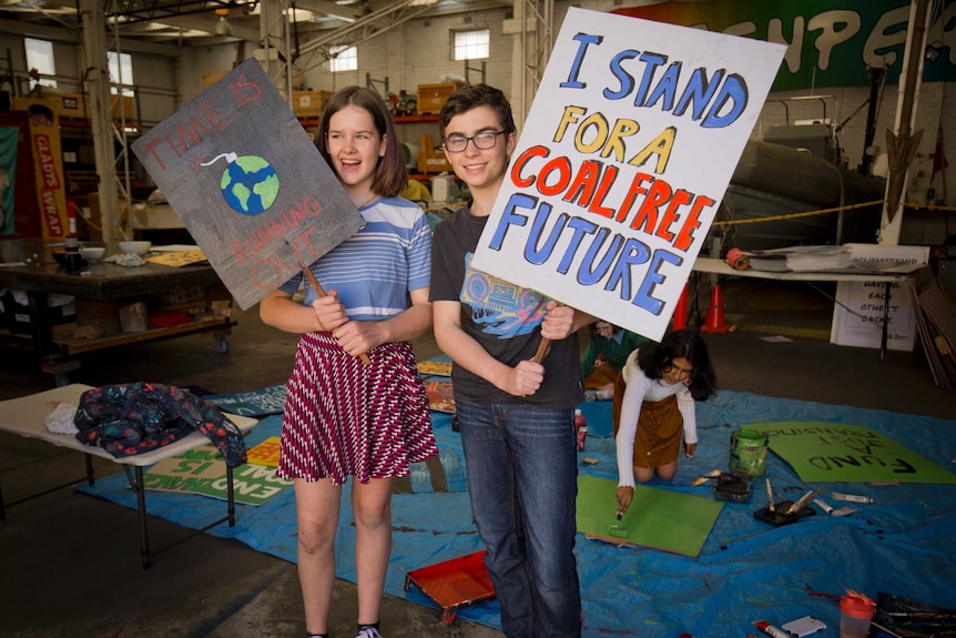 Two young people holding up placards: one reads, 'I stand for a coal free future' and the other says, 'Time is running out'.