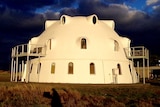 A three story white monolithic dome structure in the sunshine.