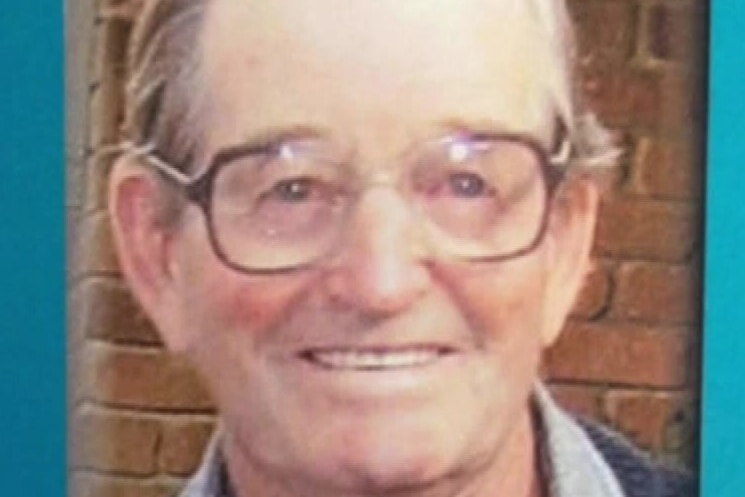A photo of a smiling man with grey hair and square glasses