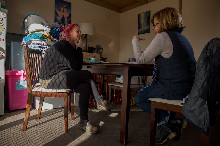 Amber and her case worker Bev sit at the kitchen table together.