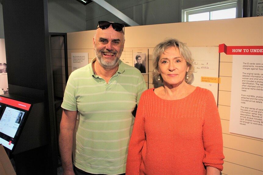 A man and a woman standing in front of an exhibition wall 