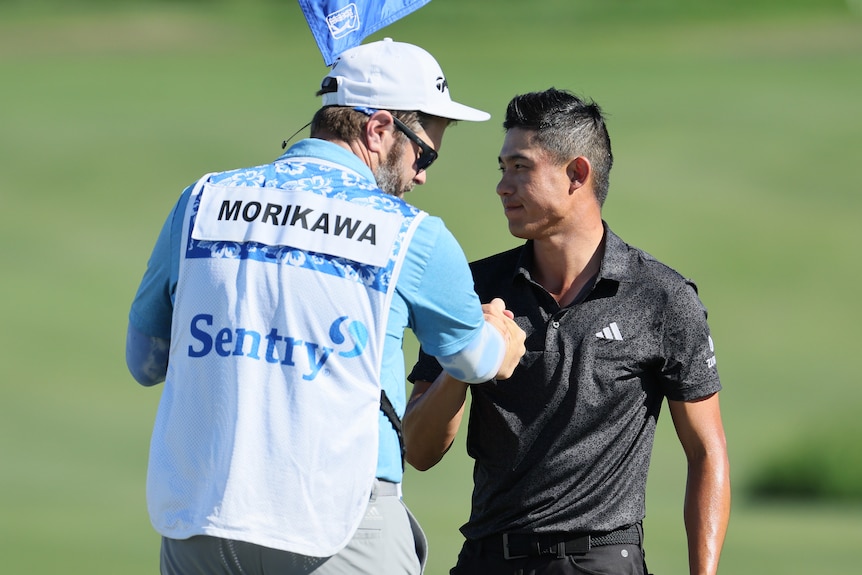 A dejected golfer shakes hands with his caddie at the end of a big tournament.