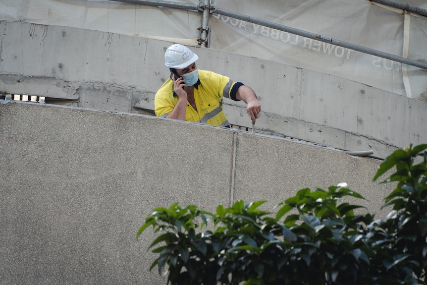 A man works on a building while talking on a phone