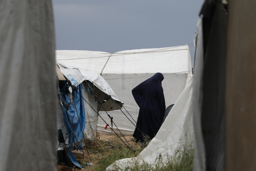 a woman in a burka amid tents