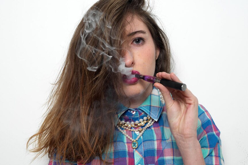 A young girl smokes an e-cigarette