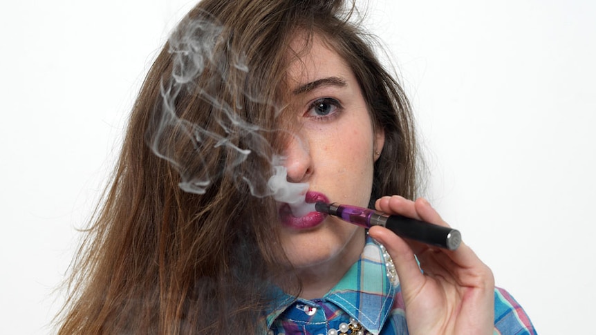 A young girl smokes an e-cigarette