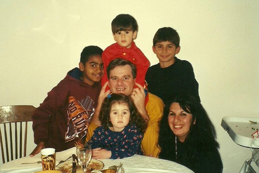 Raquel O'Brien as a little girl at the dinner table with her family.