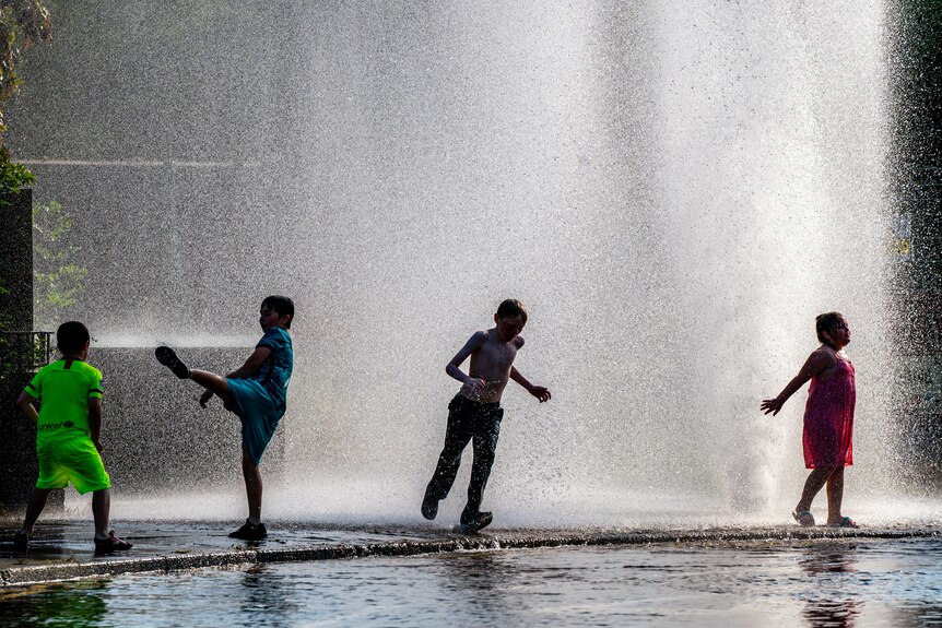 Four kids frolic in a fountain 