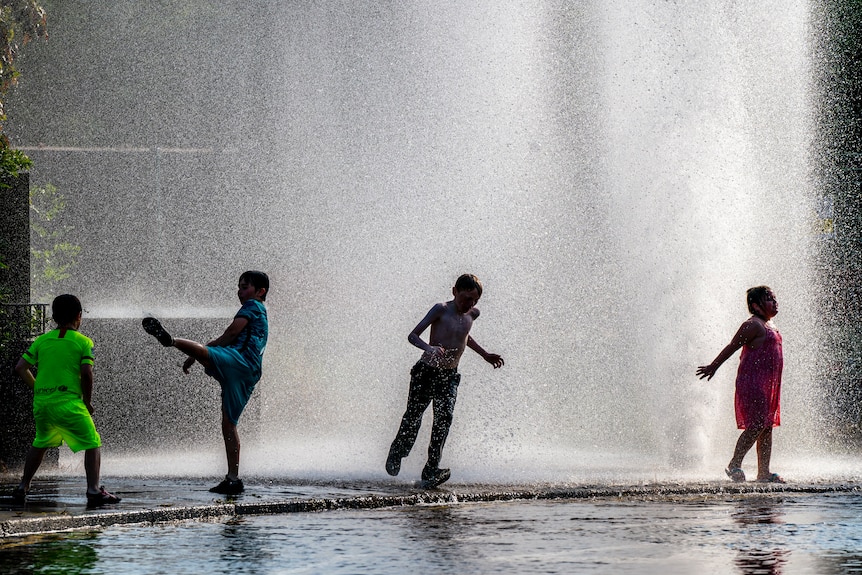 Four kids frolic in a fountain 