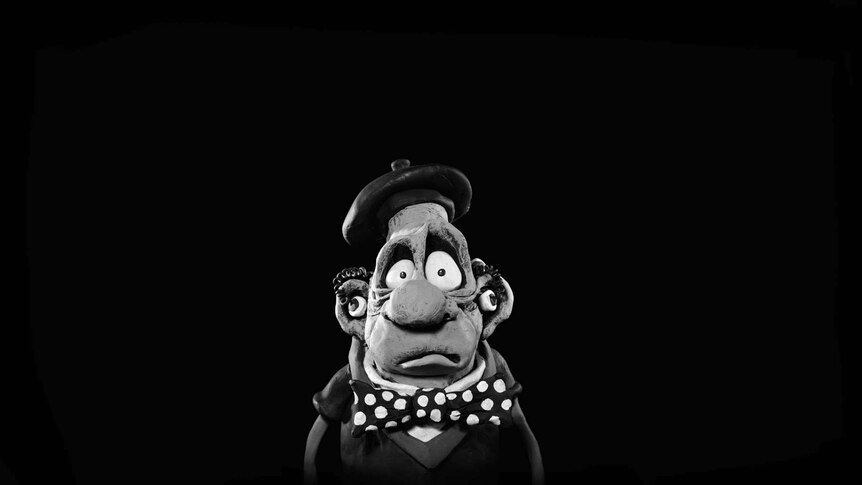 A clay character wearing a beret, a spotted bow-tie and large hearing aids.
