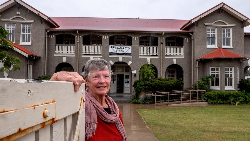 A woman stands in front of a historic building.