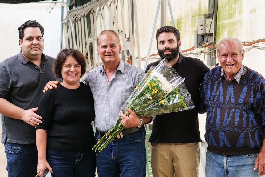 A family stand together, smiling and proud of their lifetime achievements growing flowers