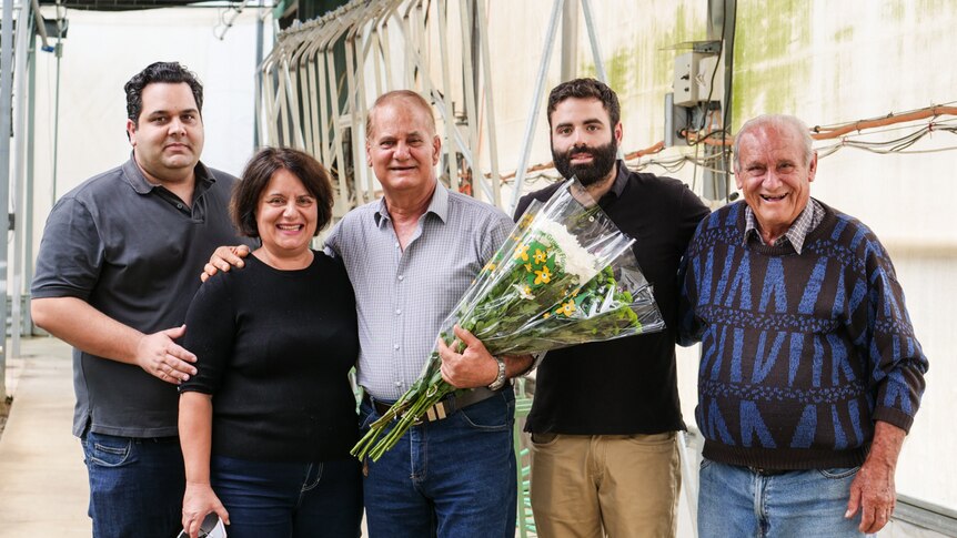 A family stand together, smiling and proud of their lifetime achievements growing flowers