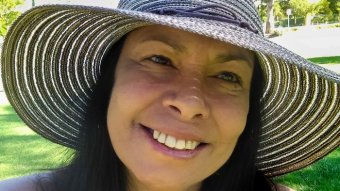 Tanya Day wears a wide-brimmed sunhat and smiles into the camera on a sunny day.