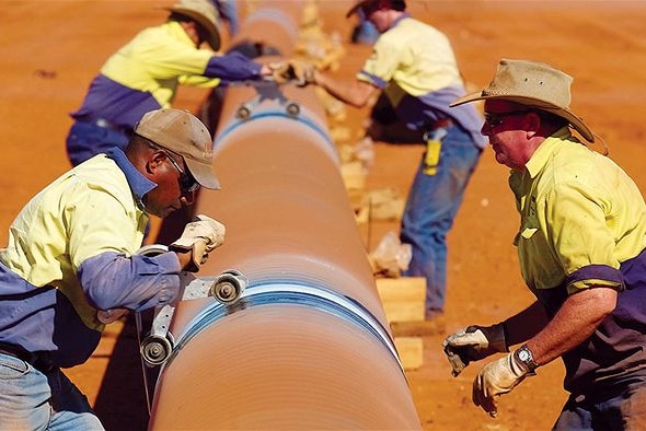 Men working to install a section of a gas pipeline.