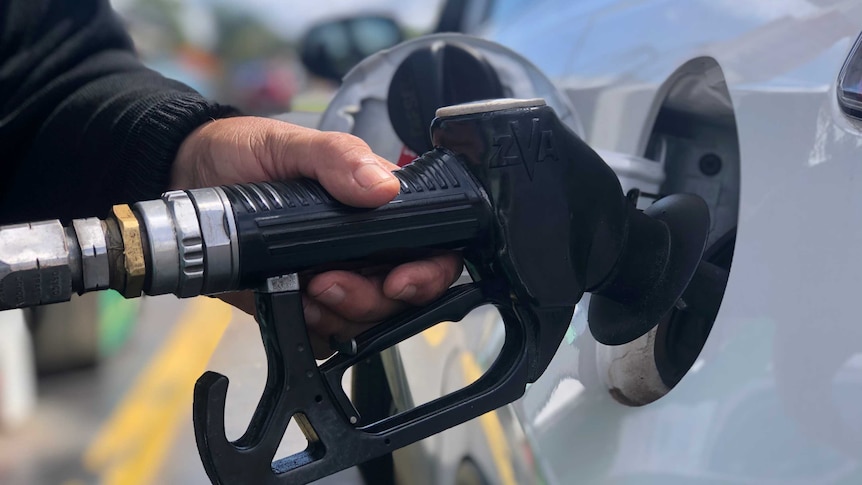 A close up of hand holding a fuel pump at the bowser