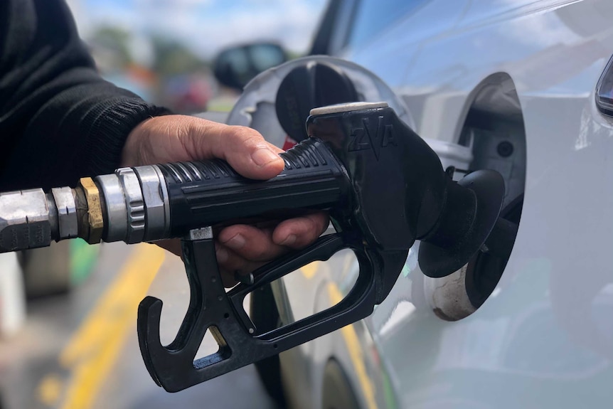 A close up of hand holding a fuel pump at the bowser