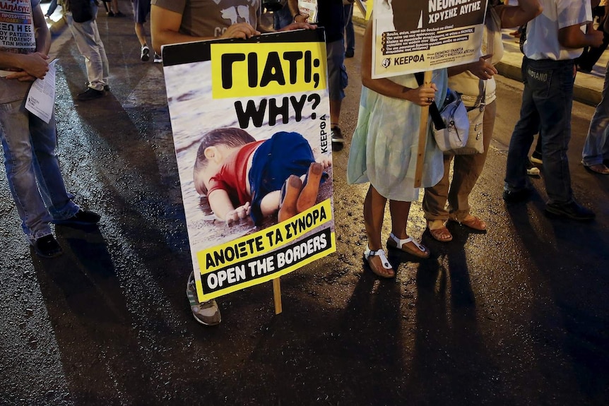 A man holds a placard with a photograph of three-year-old Syrian refugee boy Aylan Kurdi.