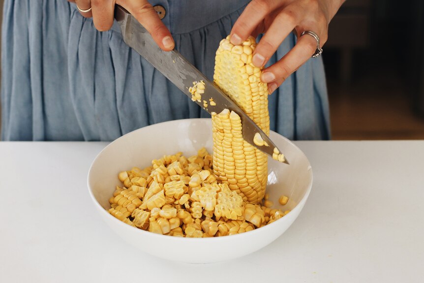 Heidi Sze demonstrates how to shave corn kernels into a bowl, for a couscous salad recipe.