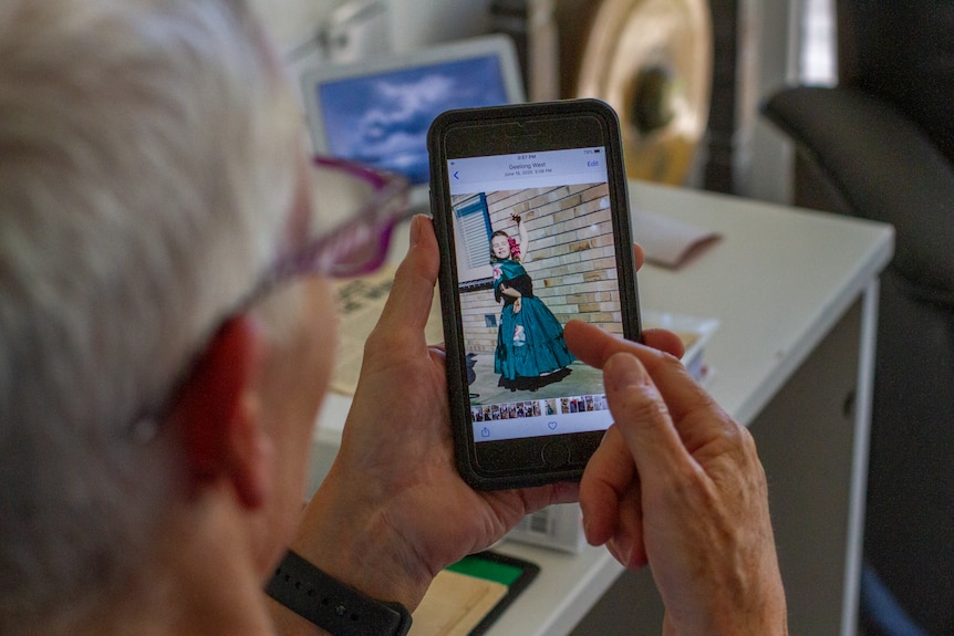 Bev Francis holds her phone which shows a picture of her as a child in a dance costume.