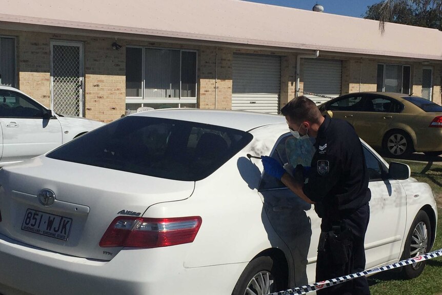 A police forensics officer dusts down a car for finger prints after a shooting.