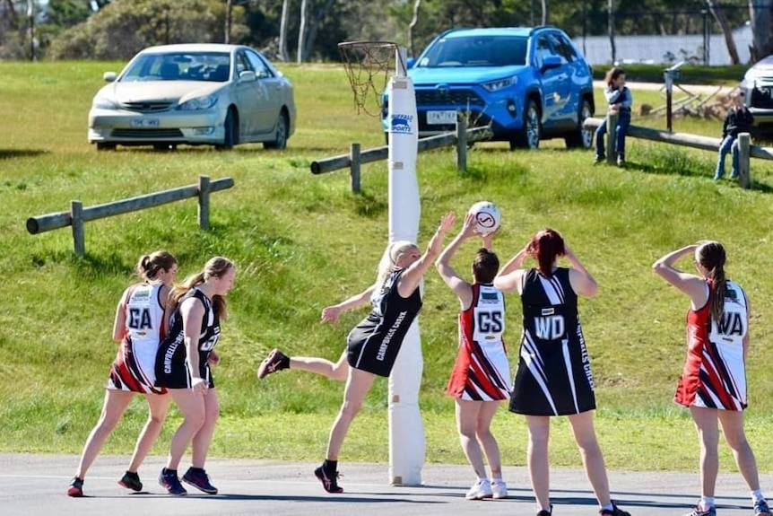 women standing at goal ring while playing netball